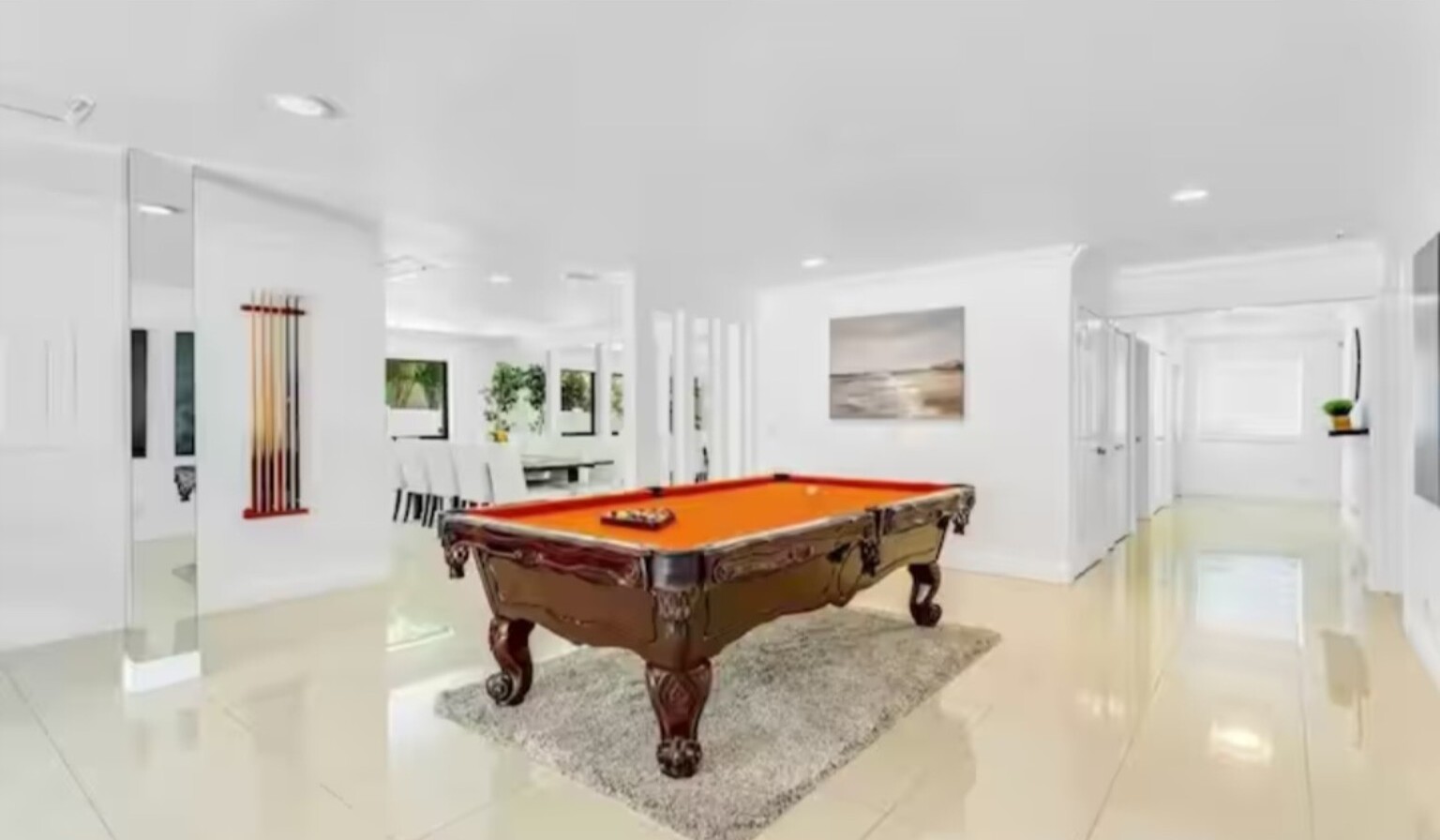 Bright game room with polished floors and a centered billiards table
